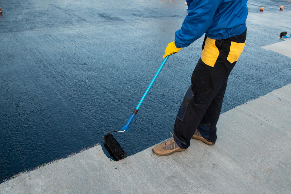 roof coating-close up of black roof coating being applied to flat roof