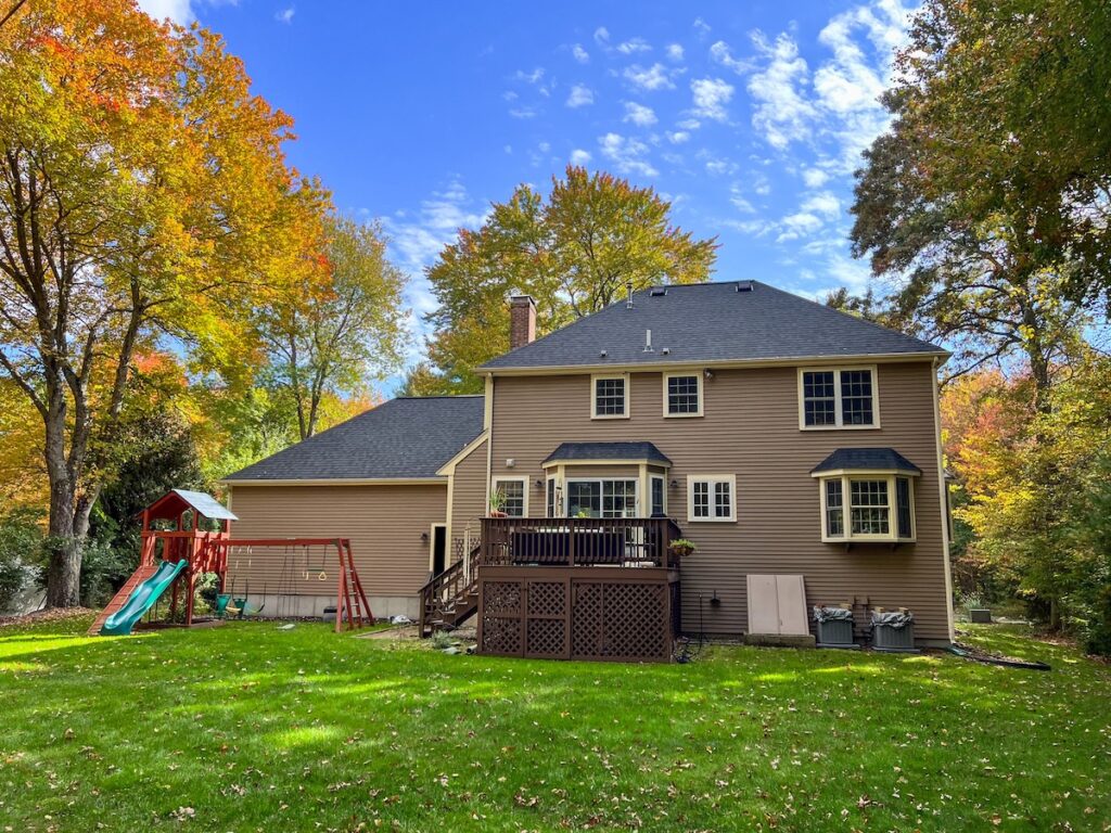 back of hip roof colonial house with swingset, deck, and bulkhead