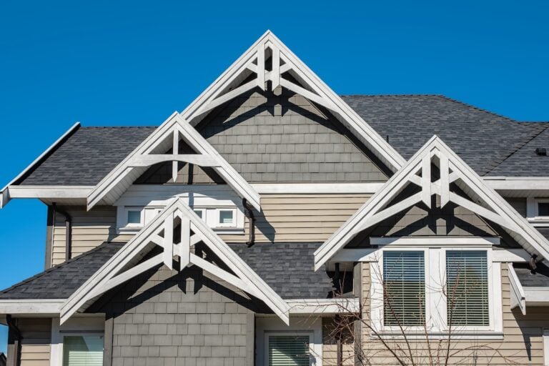 Roof shingles on top of the house against blue sky. Dark asphalt tiles on the roof background. black shingles, roof tile. Nobody, Selective focus, street photo, copy space.
