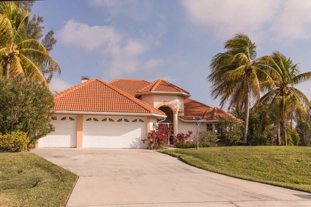 Typical Southwest Florida concrete block and stucco home in the countryside with palm trees, tropical plants and flowers, grass lawn and pine trees. Florida. South Florida single family house
