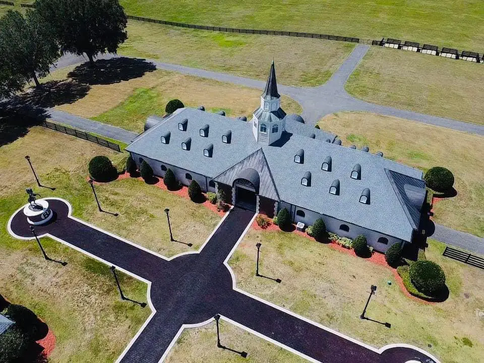 Aerial view of a gray asphalt shingle roof on a large equestrian estate building in Florida