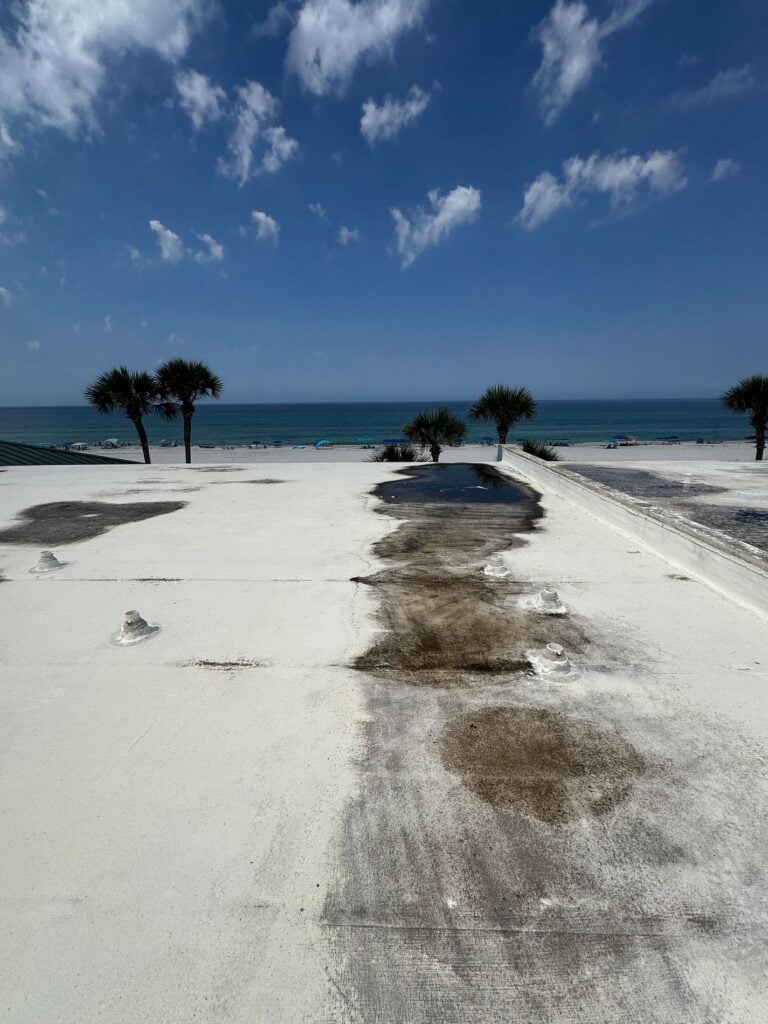 Weathered commercial flat roof with worn coating and deteriorated areas before restoration