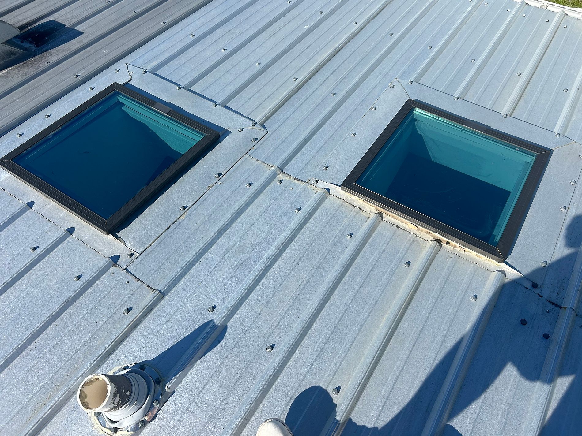 Worn skylight flashing and deteriorated sealant on a metal roof before repair