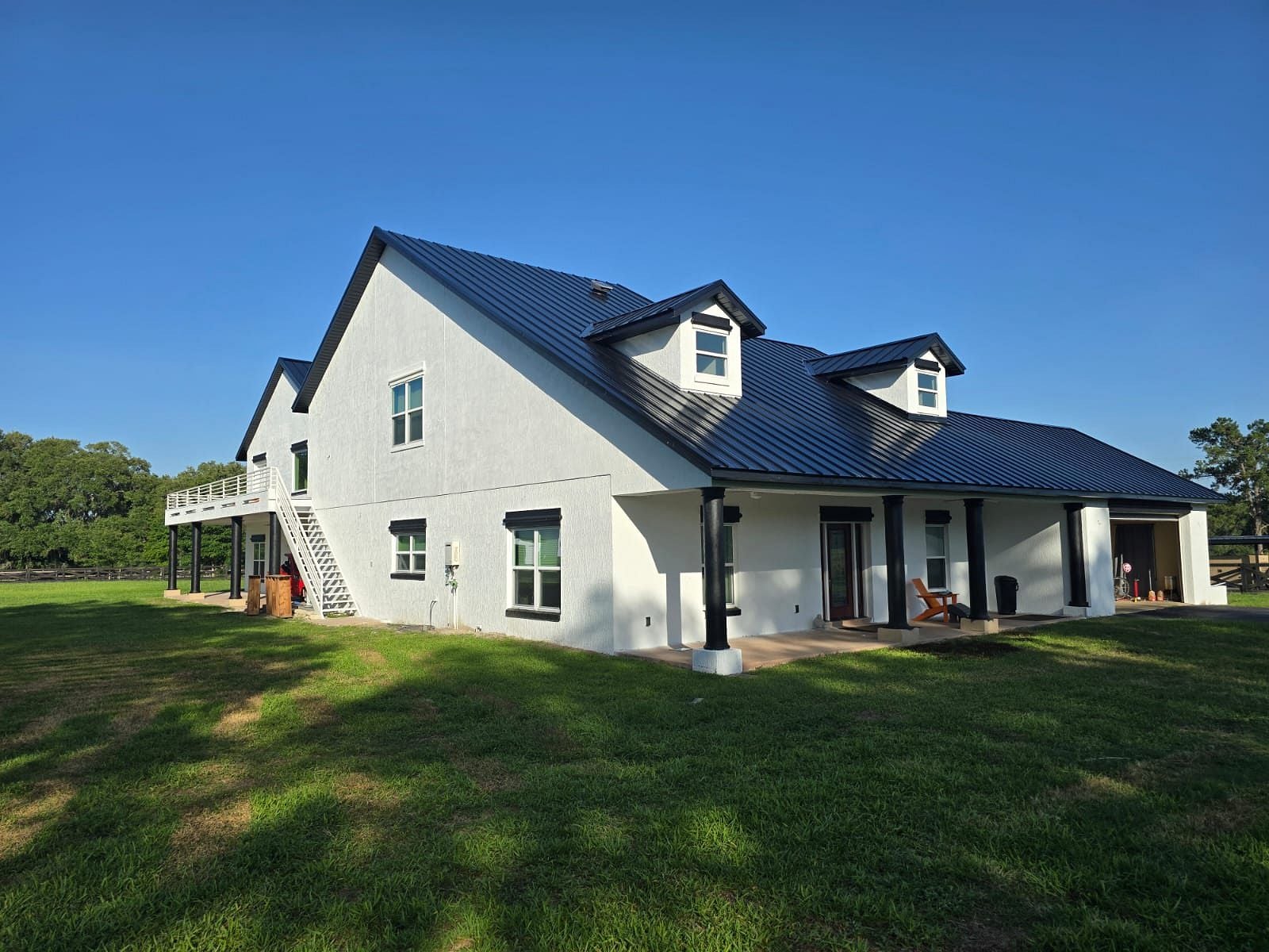 Completed black standing seam metal roof on a white residential home in Ocala, Florida