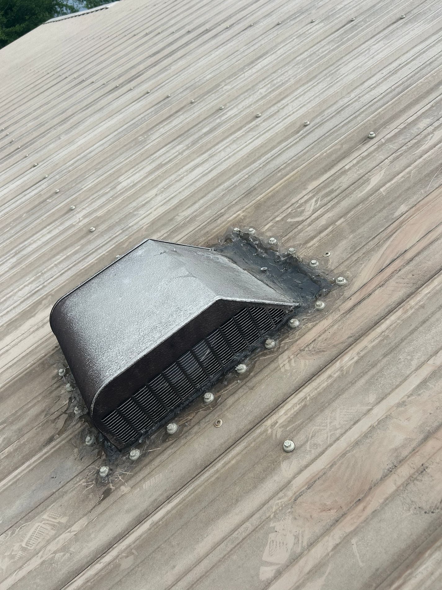 Damaged metal roof vent flashing with deteriorated sealant around the vent