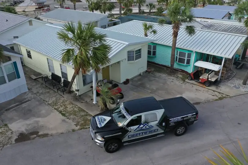 Certified Roofing Solutions truck beside homes with completed metal roofing systems in Florida