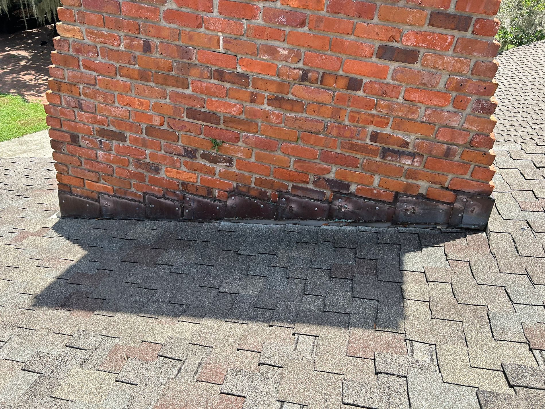 Damaged chimney flashing and worn asphalt shingles on a residential roof