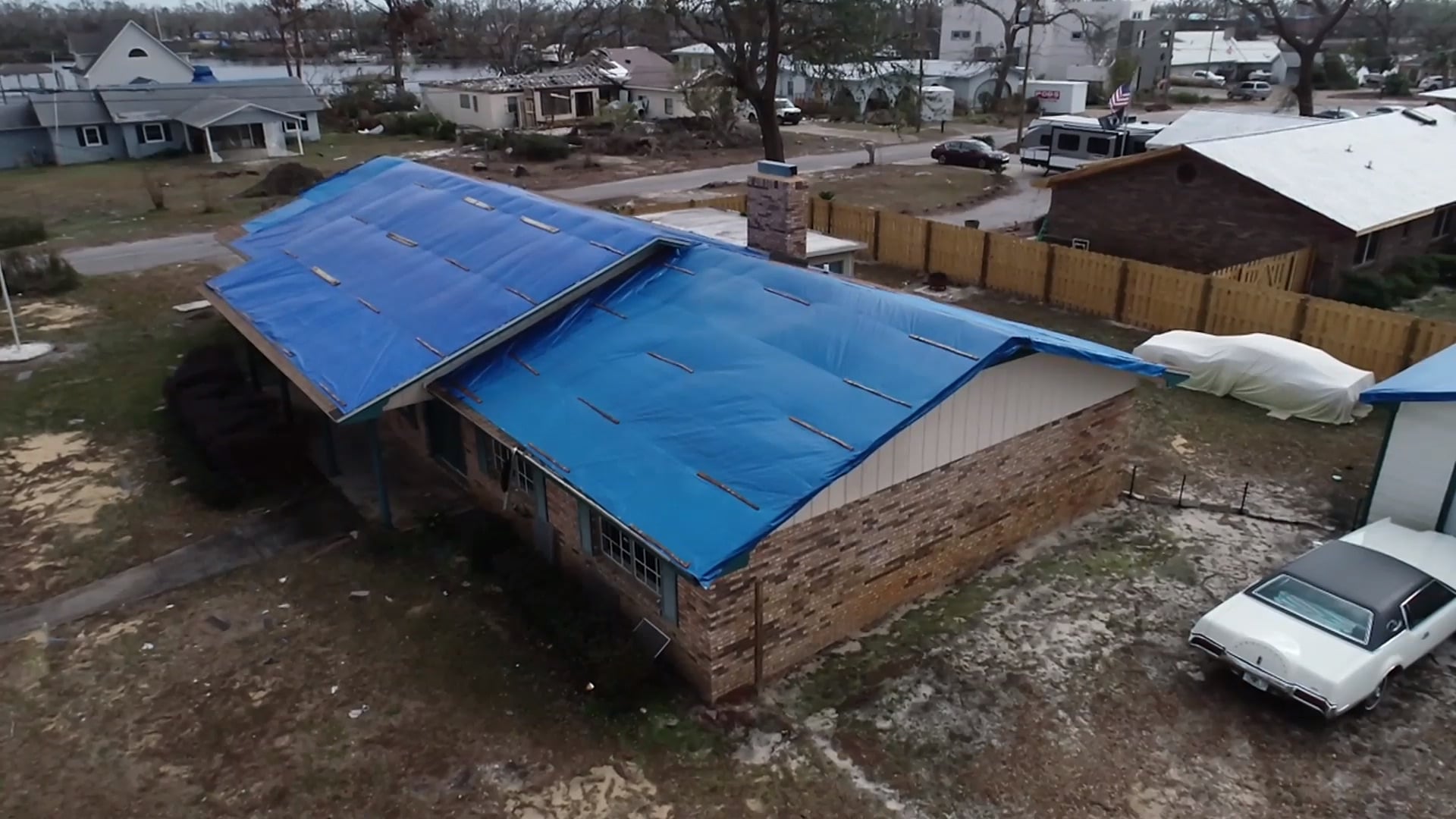 Blue emergency roof tarp installed over a storm-damaged residential roof in Florida