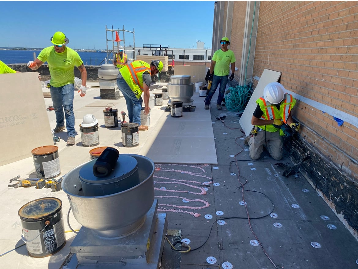 Commercial roofing crew installing a TPO membrane system on a flat roof in Florida