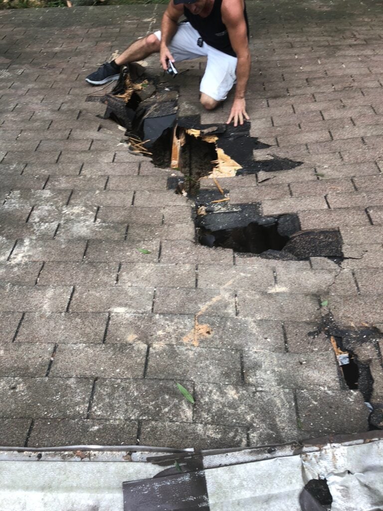 Severe roof damage with broken decking and holes caused by fallen tree limbs and debris