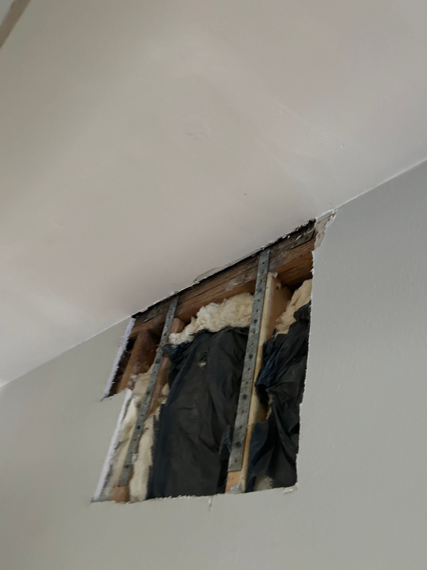 Interior ceiling and wall opened to expose damage caused by an active roof leak