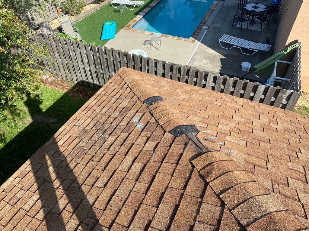 Wind-damaged asphalt shingle roof with lifted and missing shingles after a storm