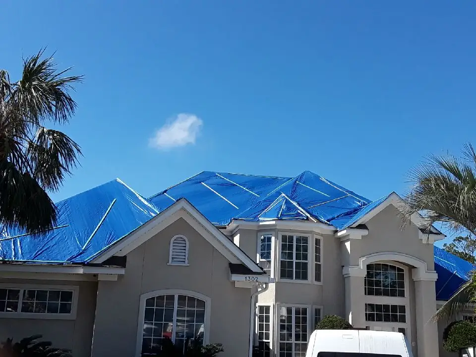 Blue emergency roof tarps installed over storm-damaged roofing on a Florida home
