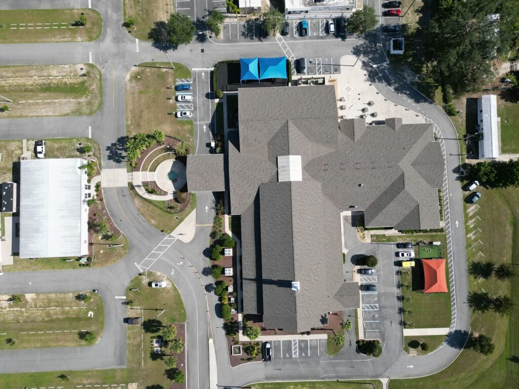 Top-down aerial view of a 24-gauge standing seam metal roof installation on a cross-shaped commercial clubhouse in Sarasota, FL.