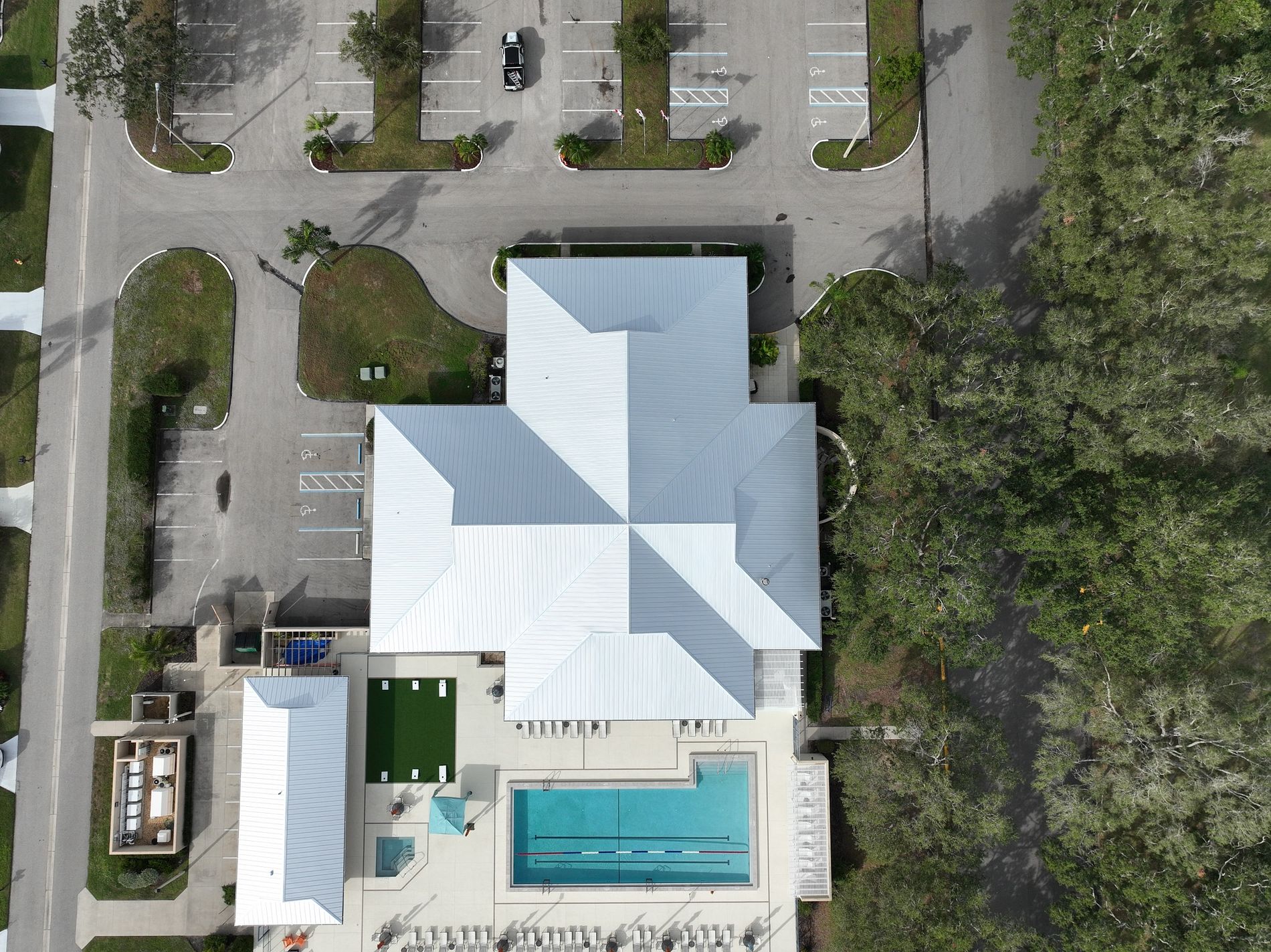 Top-down aerial view of a 24-gauge standing seam metal roof installation on a cross-shaped commercial clubhouse in Sarasota, FL.