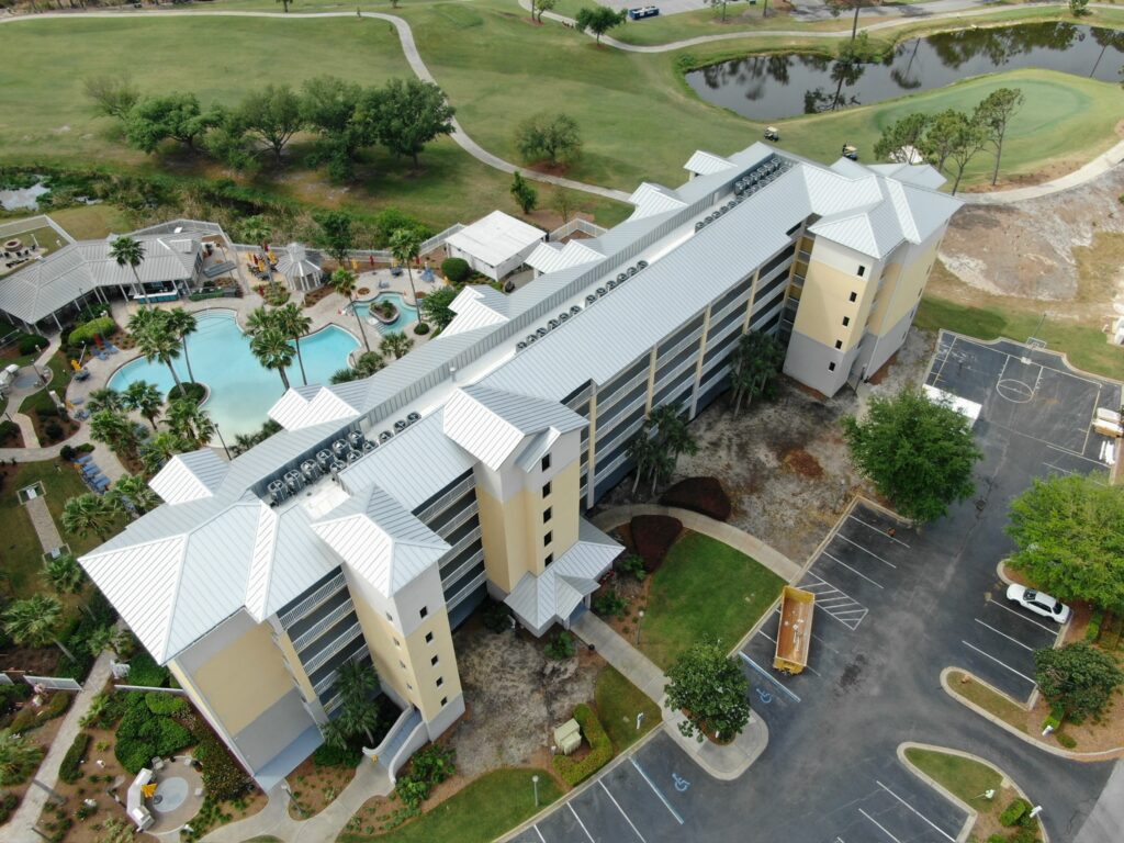 Complete view of the finished white standing seam metal roof on the main multi-story building at Marriott Legend's Edge, overlooking the pool area.