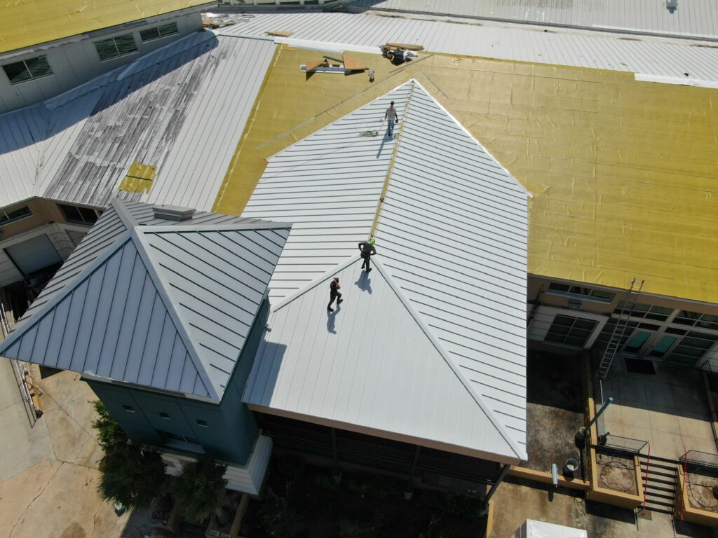 Certified Roofing Solutions crew installing .040" aluminum snap-lock standing seam panels on Bluewater Development in Panama City, FL.