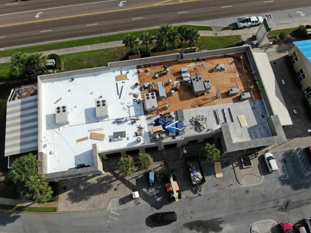 Progress aerial photo of Certified Roofing Solutions installing GAF EverGuard TPO membrane over insulation boards during a commercial reroof.