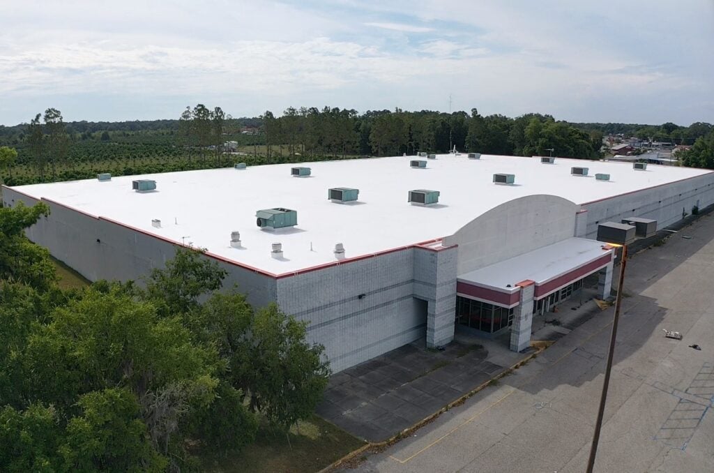 Elevated front-view photo of the Kmart commercial facility in Pace, FL featuring a restored white waterproof silicone roof system.