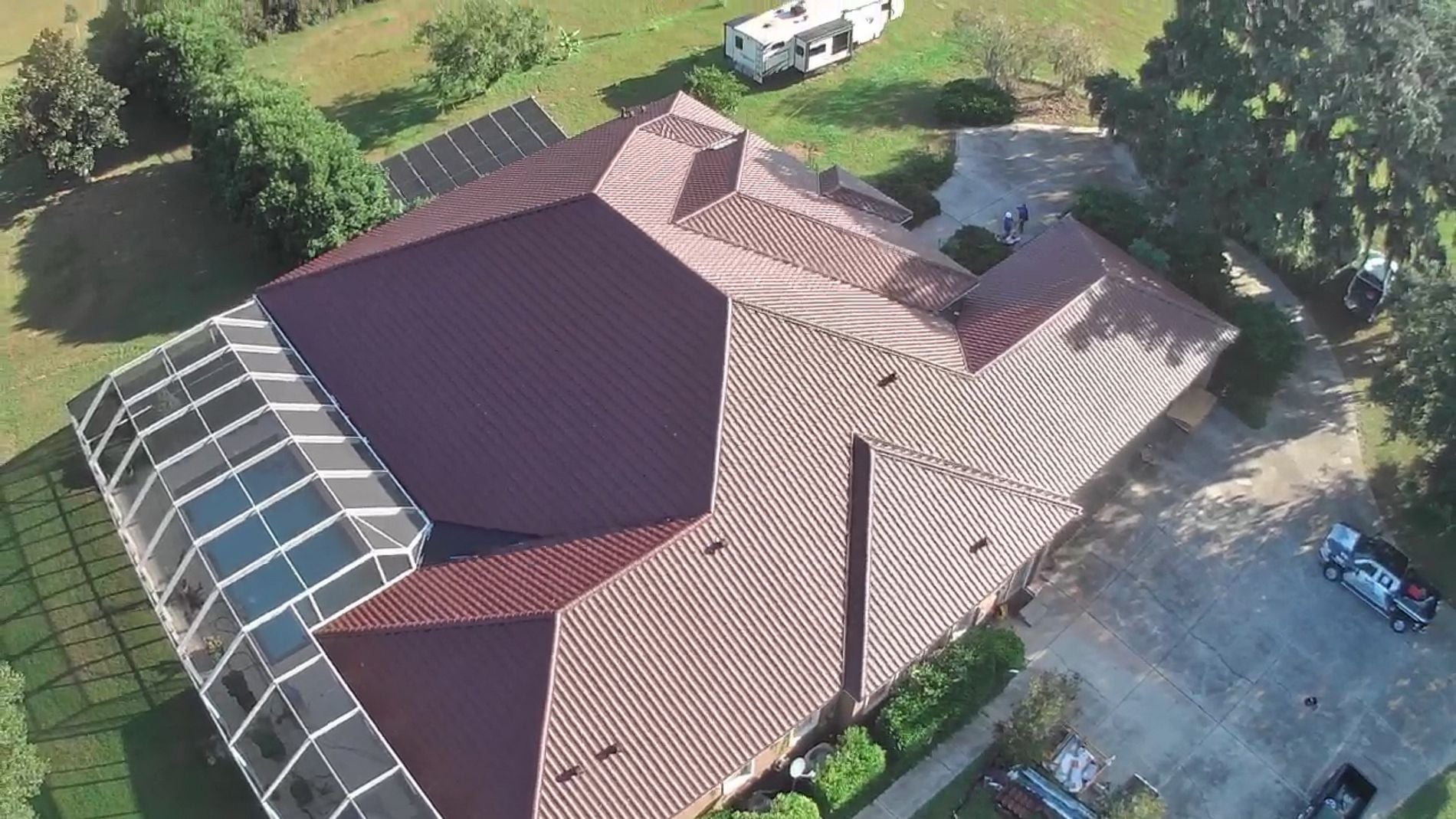 Wide top-down aerial view of a home with a pool enclosure receiving a Worthouse Supre metal tile roof in Ocala, FL.