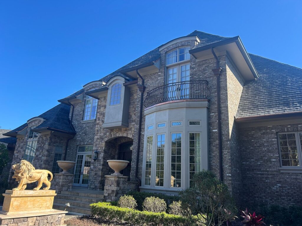 Front entrance of an executive stone home featuring a GAF Slateline designer shingle roof replacement in Ocala,