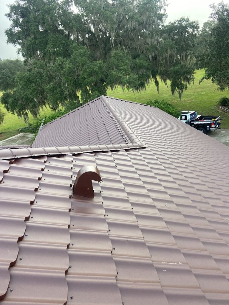 Rooftop perspective looking down a Worthouse Supre metal roof slope with roof vents toward a work truck in Ocala, FL.
